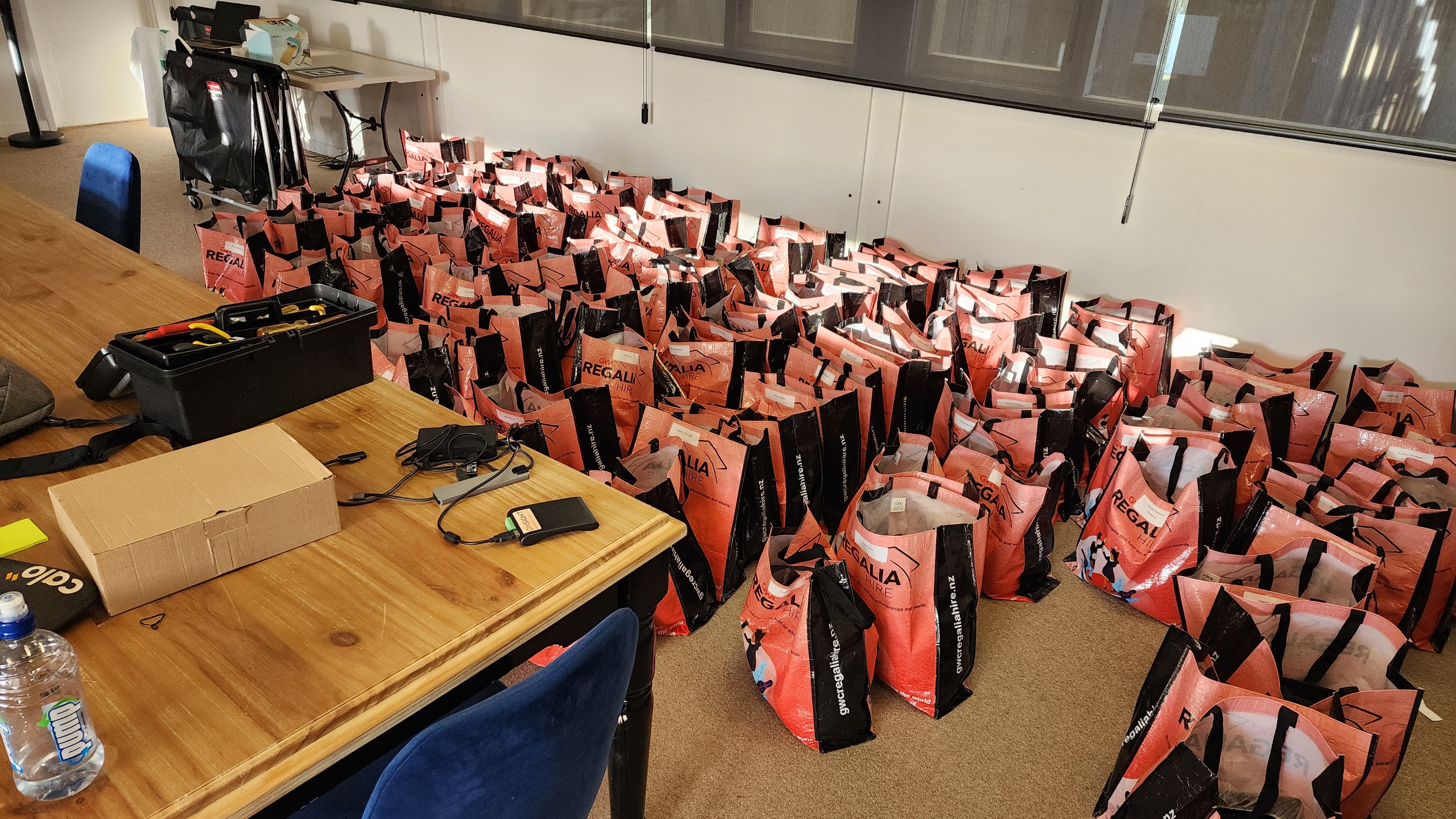 A set of bags containing regalia after a graduation ceremony, ready to be scanned for returns. Contains GWC branding on bags.